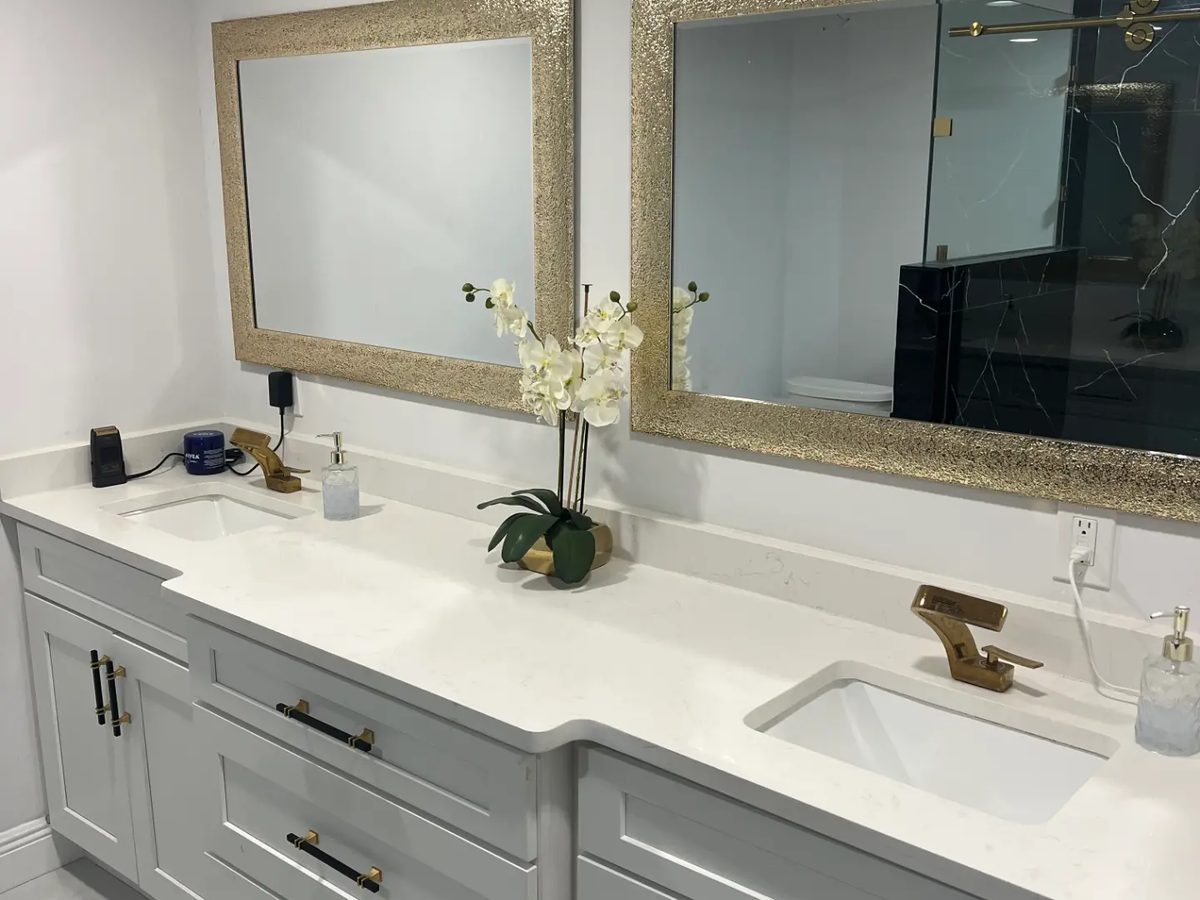 Custom gray double bathroom vanity with white quartz countertop, undermount sinks, gold faucets and framed mirrors